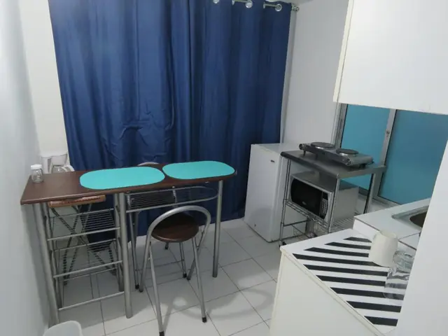 Cocina con mesa y banquetas de un estudio de Serenade Lodging Rooms